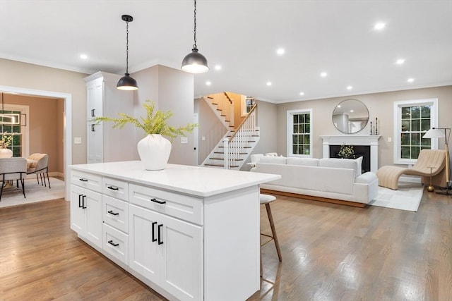 kitchen with a breakfast bar area, healthy amount of natural light, crown molding, a center island, and white cabinetry