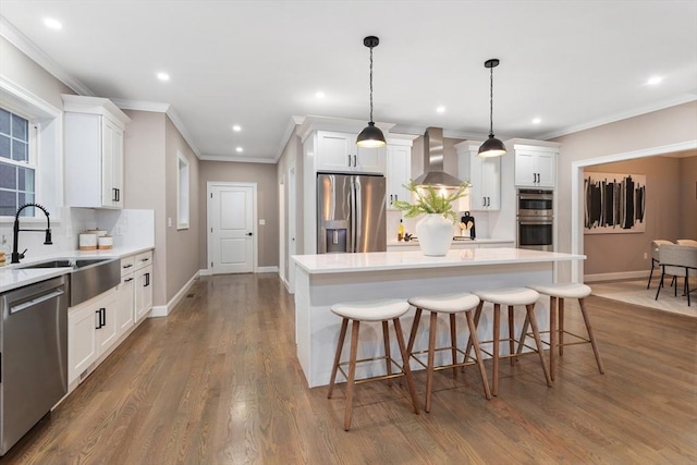 kitchen featuring stainless steel appliances, wall chimney range hood, decorative backsplash, recessed lighting, and a kitchen island
