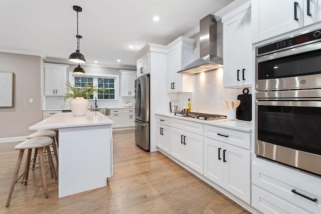 kitchen with wall chimney range hood, appliances with stainless steel finishes, a breakfast bar area, tasteful backsplash, and recessed lighting