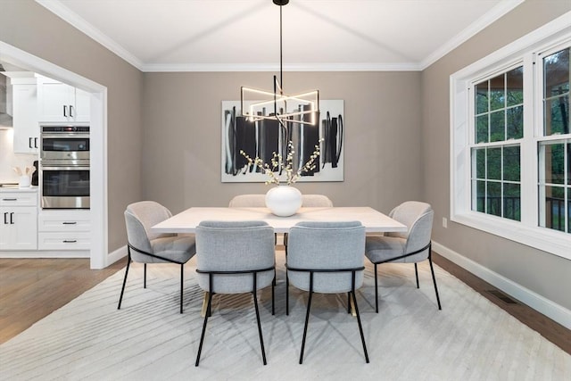 dining area featuring light wood-style flooring, baseboards, a chandelier, and crown molding