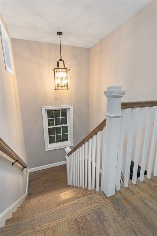 staircase featuring a chandelier, wood finished floors, and baseboards