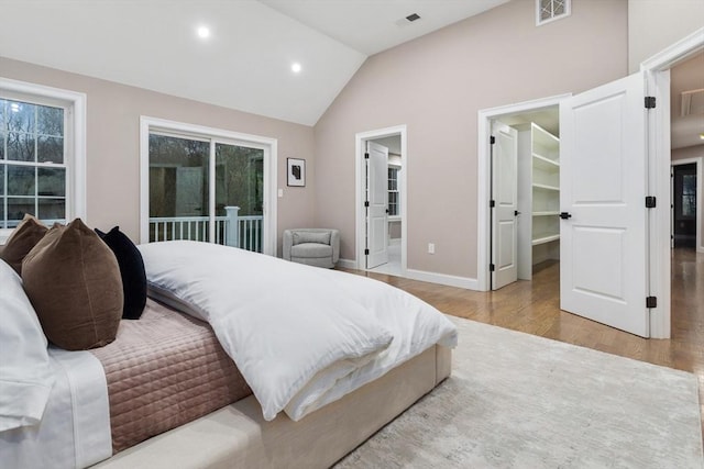 bedroom featuring wood finished floors, a walk in closet, vaulted ceiling, baseboards, and recessed lighting