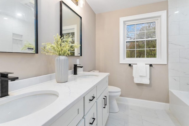 bathroom featuring marble finish floors, baseboards, toilet, a tub, and double vanity
