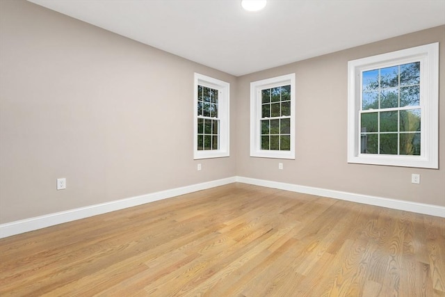 spare room featuring light wood finished floors and baseboards