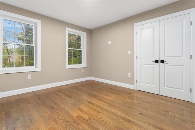 unfurnished room featuring wood finished floors, baseboards, and healthy amount of natural light