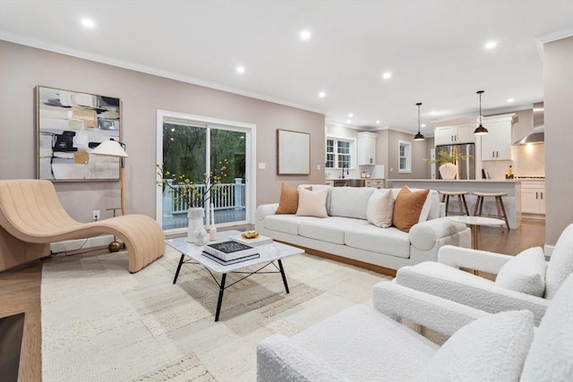 living room featuring crown molding, recessed lighting, and light wood-style floors