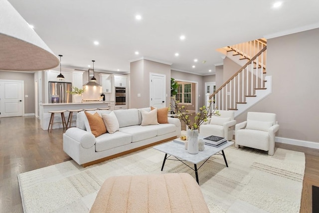 living room featuring crown molding, baseboards, recessed lighting, light wood finished floors, and stairs