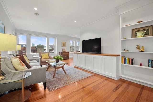 living room featuring built in shelves, light hardwood / wood-style floors, and ornamental molding