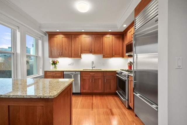 kitchen with sink, stainless steel appliances, light stone counters, crown molding, and light hardwood / wood-style floors