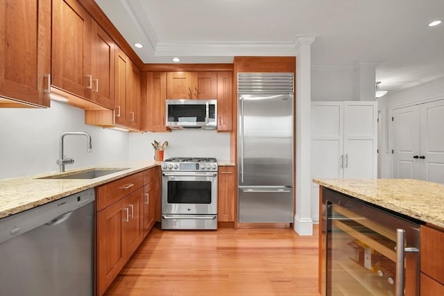 kitchen with sink, light stone countertops, stainless steel appliances, and beverage cooler