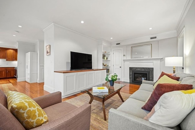 living room featuring light hardwood / wood-style floors, ornamental molding, and a premium fireplace