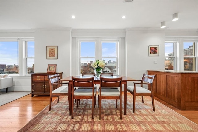 dining room with light wood-type flooring, plenty of natural light, and ornamental molding