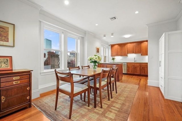 dining space with light hardwood / wood-style floors, ornamental molding, and sink