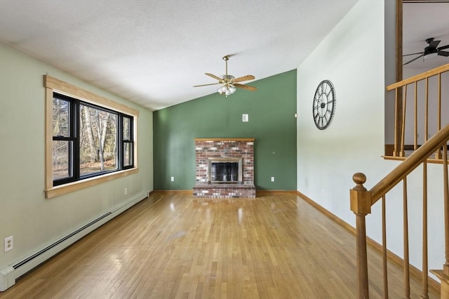 unfurnished living room featuring lofted ceiling, ceiling fan, baseboard heating, a fireplace, and light hardwood / wood-style floors