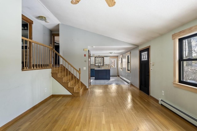 entrance foyer featuring baseboard heating, a healthy amount of sunlight, lofted ceiling, and light hardwood / wood-style floors