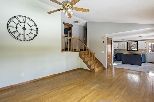 unfurnished living room with lofted ceiling, sink, ceiling fan, and light hardwood / wood-style flooring