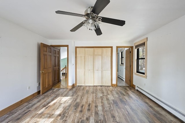 unfurnished bedroom featuring hardwood / wood-style floors, a baseboard radiator, a closet, and ceiling fan