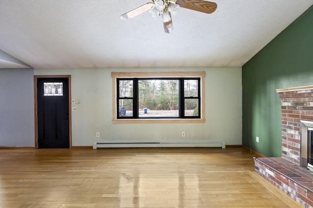 foyer entrance featuring a fireplace, lofted ceiling, baseboard heating, a textured ceiling, and light hardwood / wood-style flooring