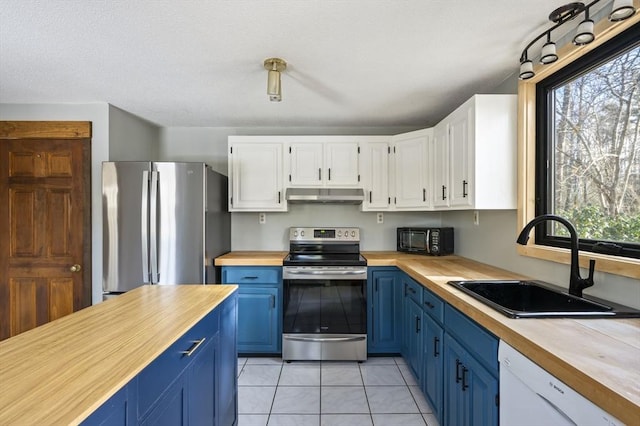 kitchen with blue cabinets, sink, light tile patterned floors, stainless steel appliances, and white cabinets