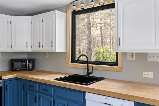 kitchen with sink, butcher block countertops, blue cabinetry, white cabinetry, and white dishwasher