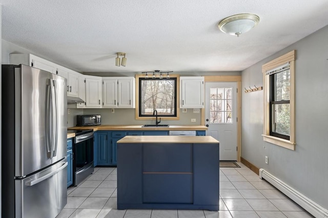 kitchen with white cabinetry, a baseboard radiator, appliances with stainless steel finishes, and blue cabinets