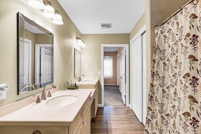 full bath with baseboards, visible vents, vanity, and wood finished floors