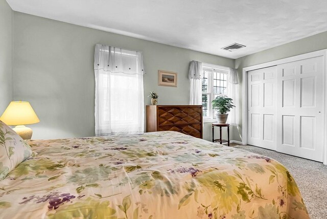 bedroom with visible vents, a closet, and carpet flooring