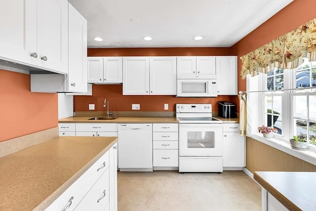 kitchen with white cabinetry, a sink, light countertops, and white appliances