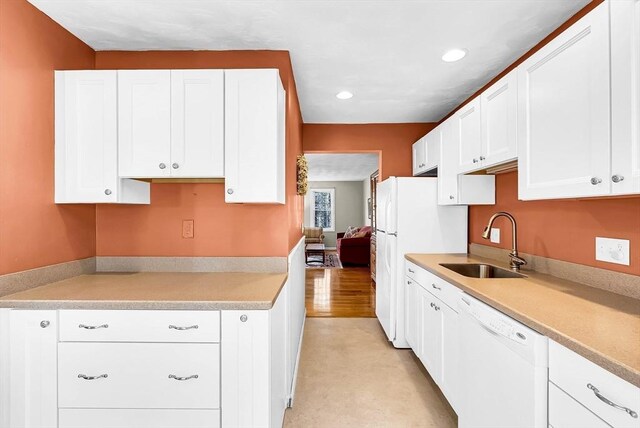 kitchen with white cabinetry, a sink, and white appliances