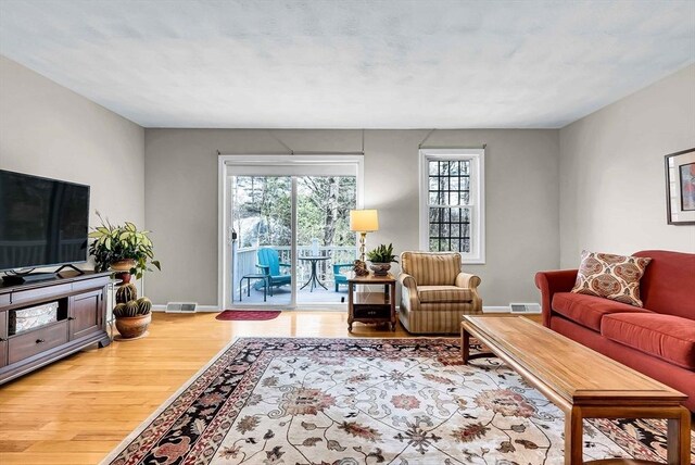 living area featuring baseboards, visible vents, and wood finished floors