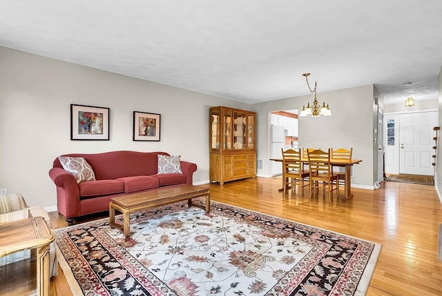 living room featuring baseboards, a notable chandelier, and light wood finished floors