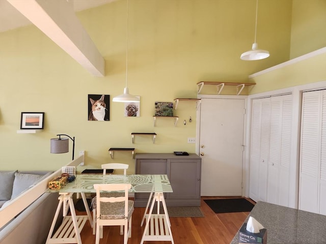 kitchen with decorative light fixtures, a high ceiling, dark hardwood / wood-style flooring, and a breakfast bar