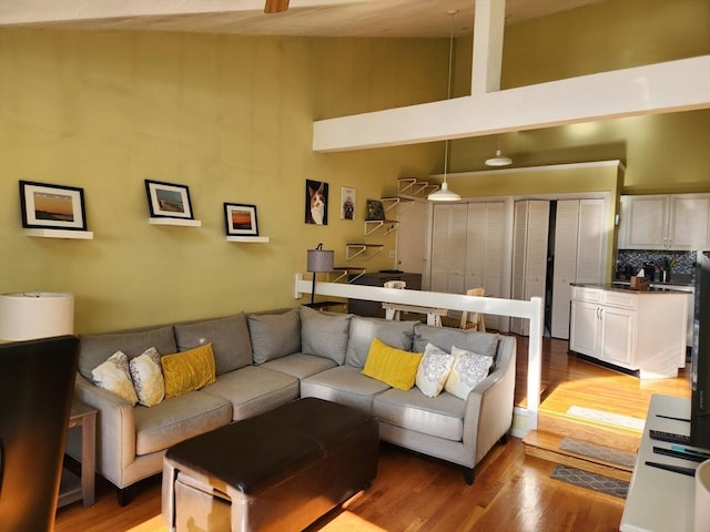 living room with light hardwood / wood-style floors and a towering ceiling