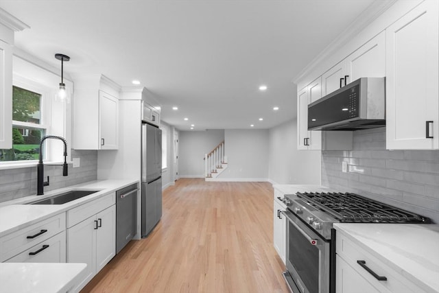 kitchen featuring white cabinetry, appliances with stainless steel finishes, baseboards, and a sink