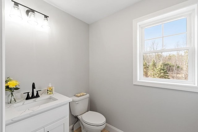 half bath with vanity, toilet, and baseboards