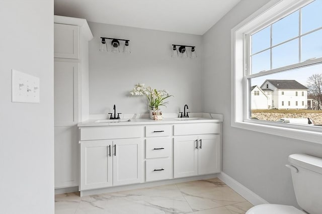 full bath featuring baseboards, marble finish floor, toilet, and a sink