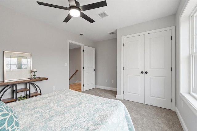 bedroom with visible vents, a closet, light colored carpet, and multiple windows