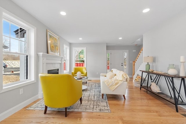 living area featuring stairway, a high end fireplace, recessed lighting, and light wood-style flooring