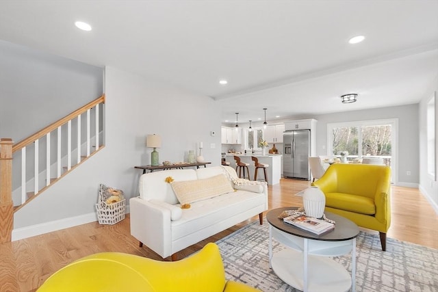living area with stairway, baseboards, recessed lighting, and light wood-type flooring