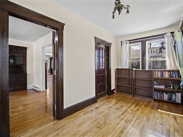 empty room featuring crown molding, baseboards, a baseboard radiator, and hardwood / wood-style flooring