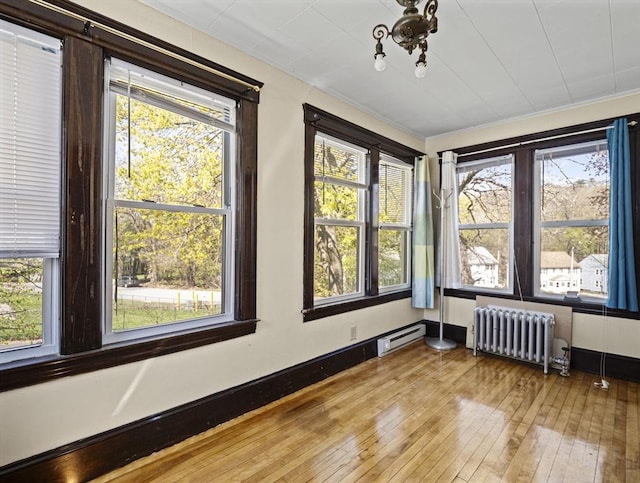 interior space with radiator, plenty of natural light, baseboard heating, and hardwood / wood-style floors