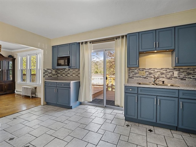kitchen featuring a sink, radiator heating unit, blue cabinetry, and light countertops