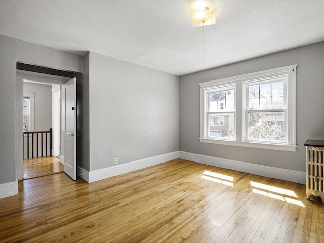 spare room with radiator heating unit, baseboards, plenty of natural light, and hardwood / wood-style floors