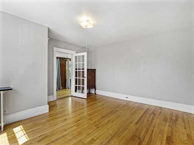 spare room featuring light wood-style floors, baseboards, and french doors