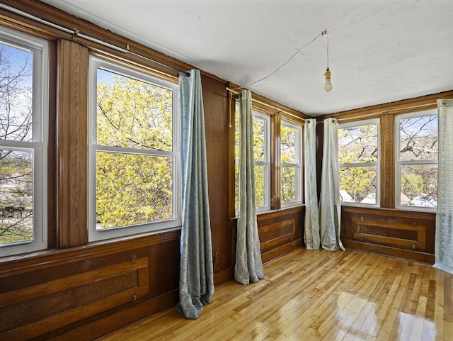sunroom / solarium featuring wood walls, a wealth of natural light, and hardwood / wood-style flooring