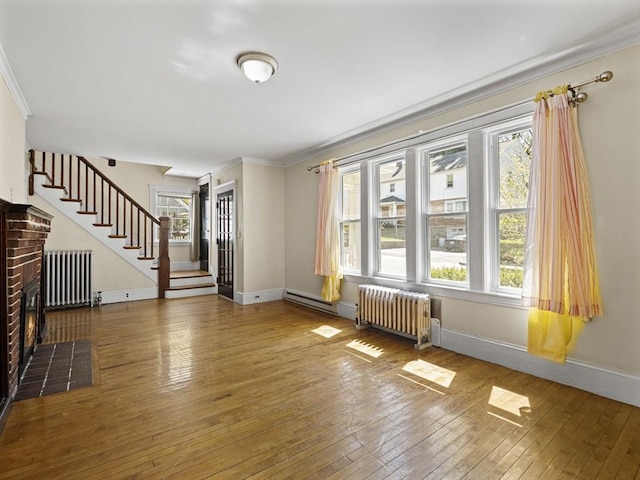 unfurnished living room featuring crown molding, stairs, radiator heating unit, and hardwood / wood-style floors