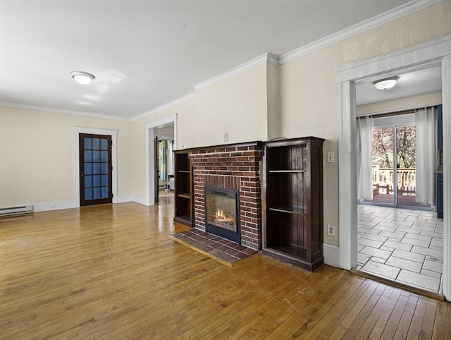unfurnished living room with wood-type flooring, ornamental molding, baseboards, and a brick fireplace