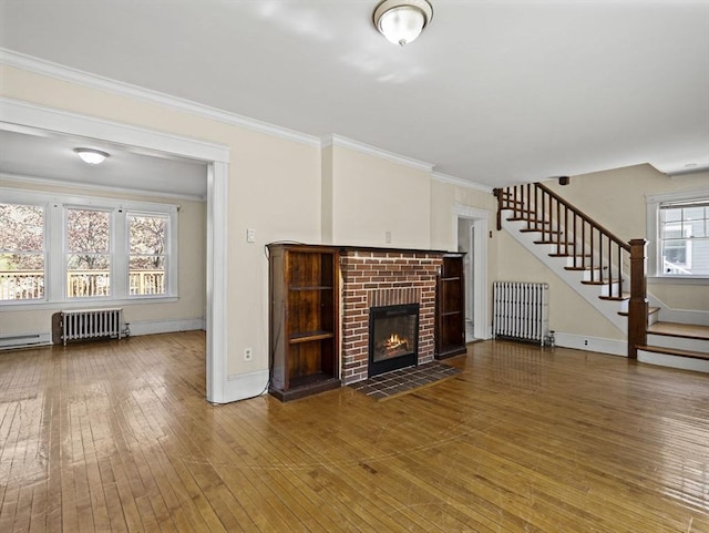 unfurnished living room featuring radiator, stairs, and hardwood / wood-style flooring