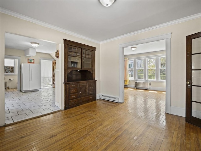 unfurnished room featuring radiator heating unit, a baseboard radiator, ornamental molding, and hardwood / wood-style flooring