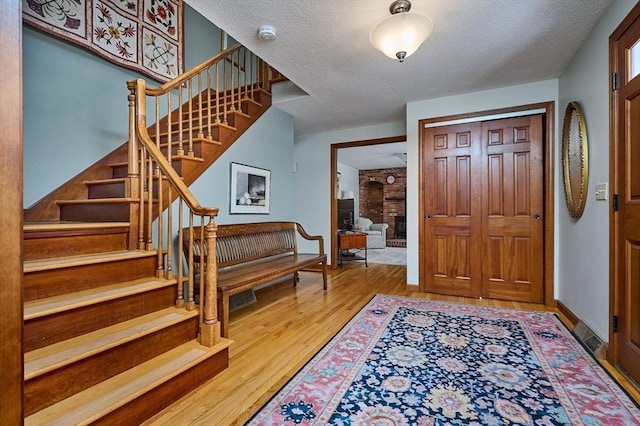 entrance foyer featuring wood-type flooring, a textured ceiling, and a fireplace